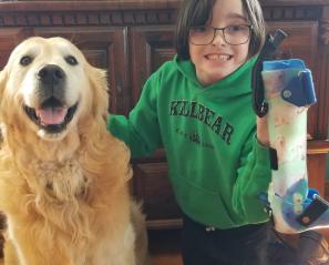 Lexi posing with her dog Cooper as she holds up her AFOs.