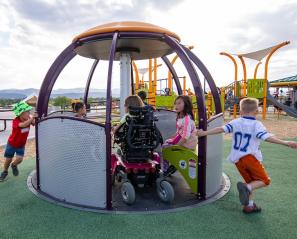 children playing on accessible merry go round