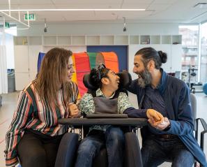 Two adults with a child on a wheel chair