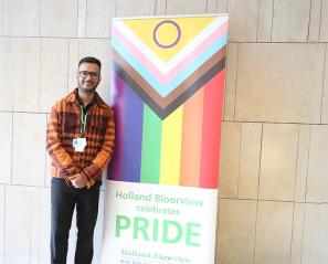 Rajpreet (Raj) Singh Sandhu standing in front of a flag