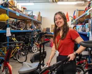 A young woman smiles and stands in a room of therapeutic recreation equipment.