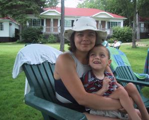 Woman with white sun hat in beach chair holding young boy