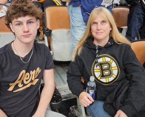 A teenage boy and his mom sit together at a hockey game.