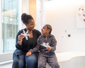 An adult with a child holding some holidays stars