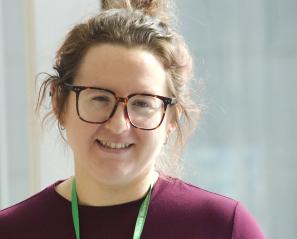 Woman with glasses and brown hair in updo smiles