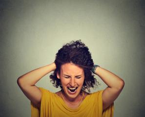 Woman grabs hair and grimaces