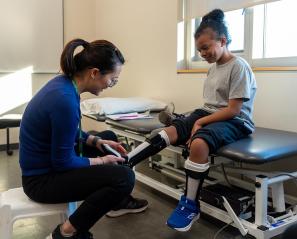 An adult helps a kid to put on the orthotic leg