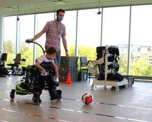 A child using the Trexo to kick a soccer ball indoors