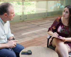 Woman with clipboard sits across from man
