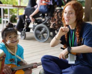 girl wearing nasal prongs holds guitar and sings with woman