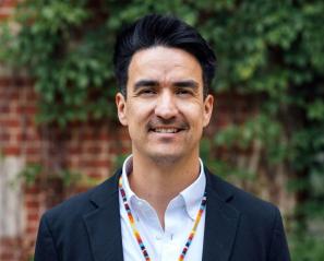 Man with dark hair and colourful necklace