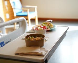 Bowls of food placed on a table in a hospital room.