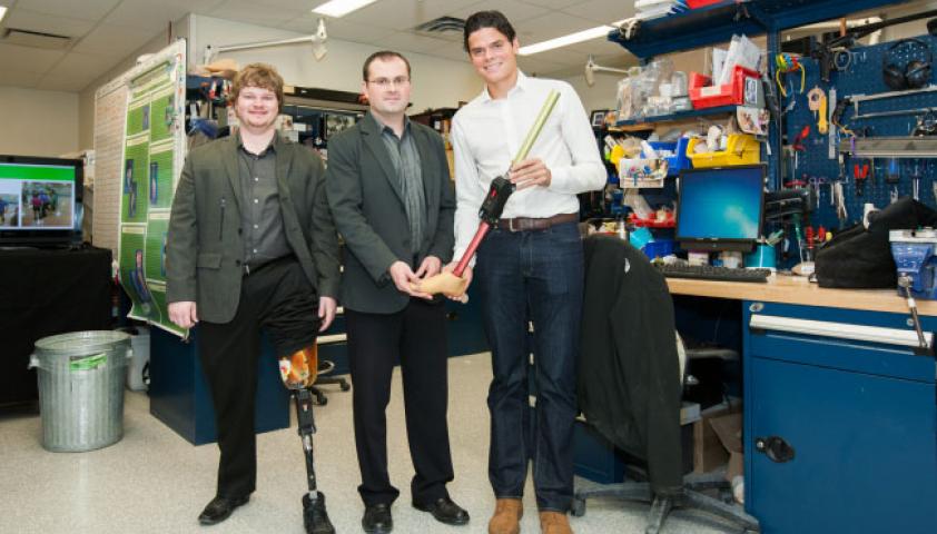 A young man with a prosthetic leg standing next to a scientist 