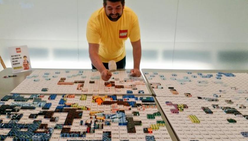 Man with a yellow shirt putting Legos together