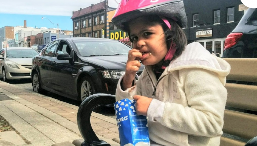 Lilly eating popcorn while wearing a pink helmet