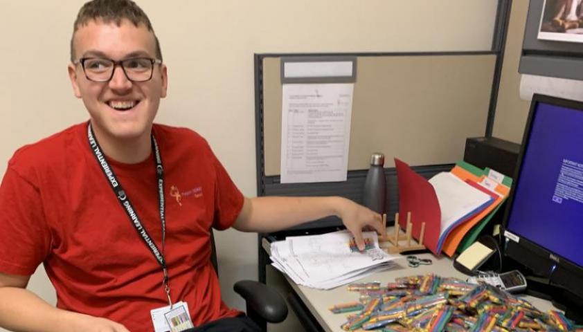 Andrew working at his desk as he smiles at the camera.