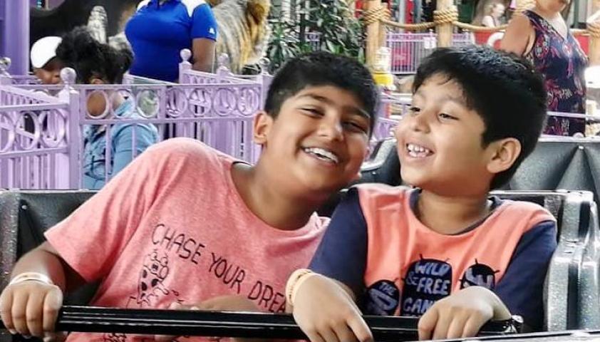 Both boys smiling on a rollercoaster. 