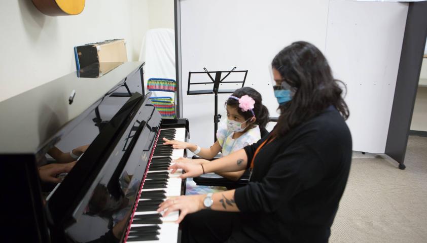 Young girl and therapist playing piano. 