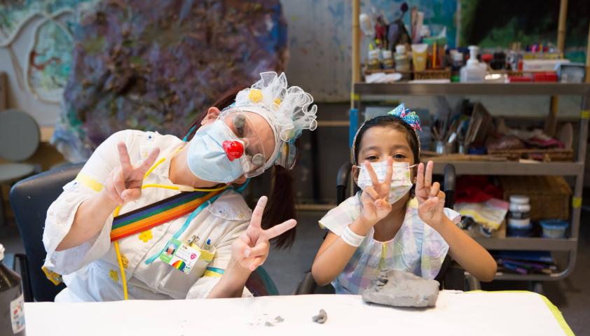 Nurse Flutter and child doing art and holding up peace signs.