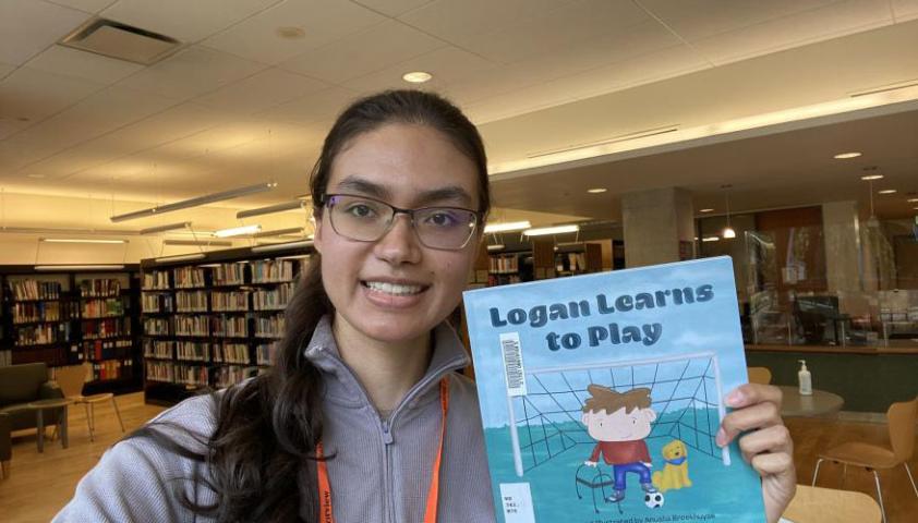 Anusha holding her book Logan Learns to Play