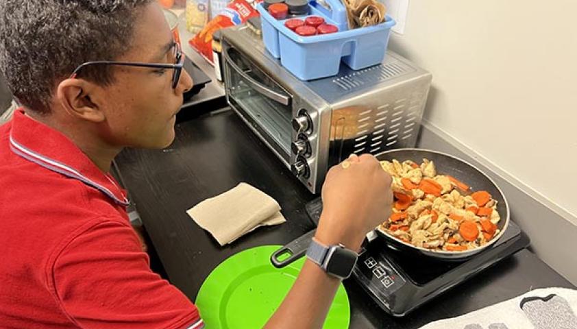 A teenager is cooking in a kitchen