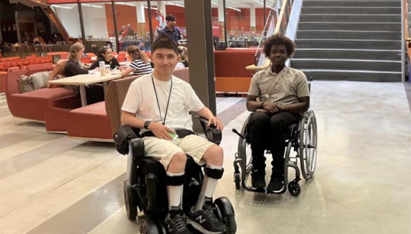 Two teenagers with wheelchair in an indoor setting