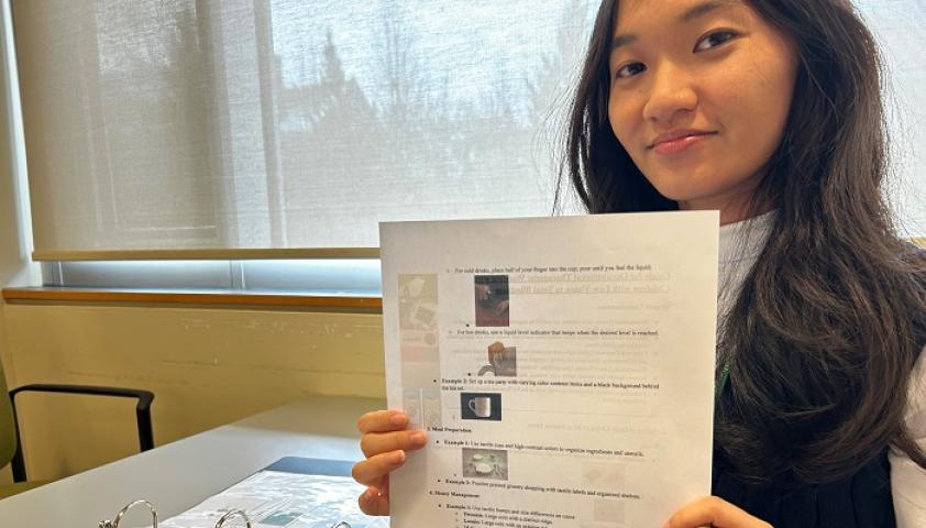Denica holds up a worksheet from a vision binder