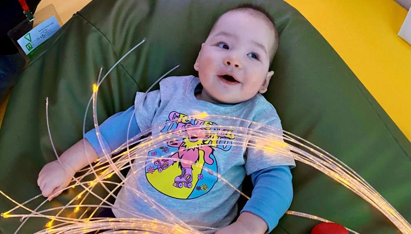 James as a baby, lying on a bean bag with some toys and LED light strips around it