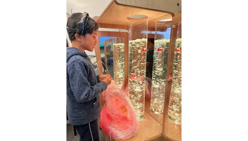 A child wearing a BCI headset, playing with a sensory bubble tube.