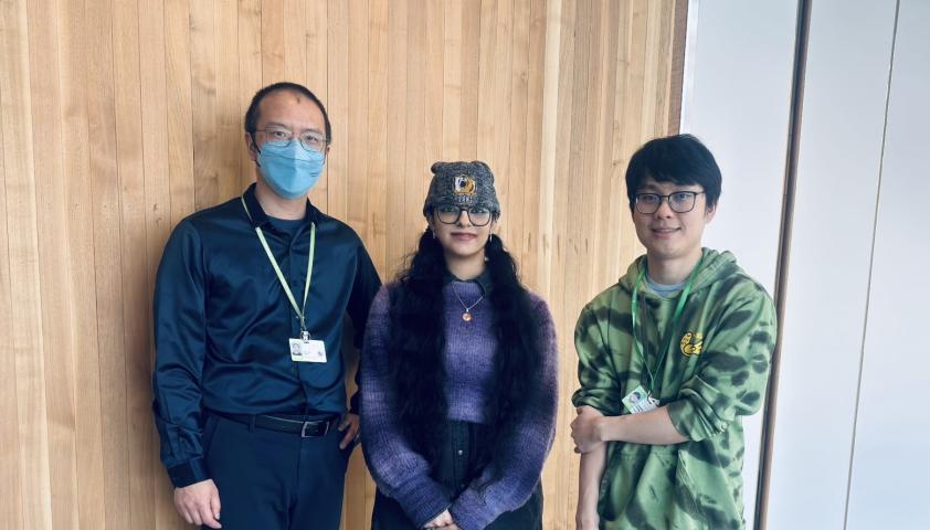 three adults standing in front of a wall with wood panelling