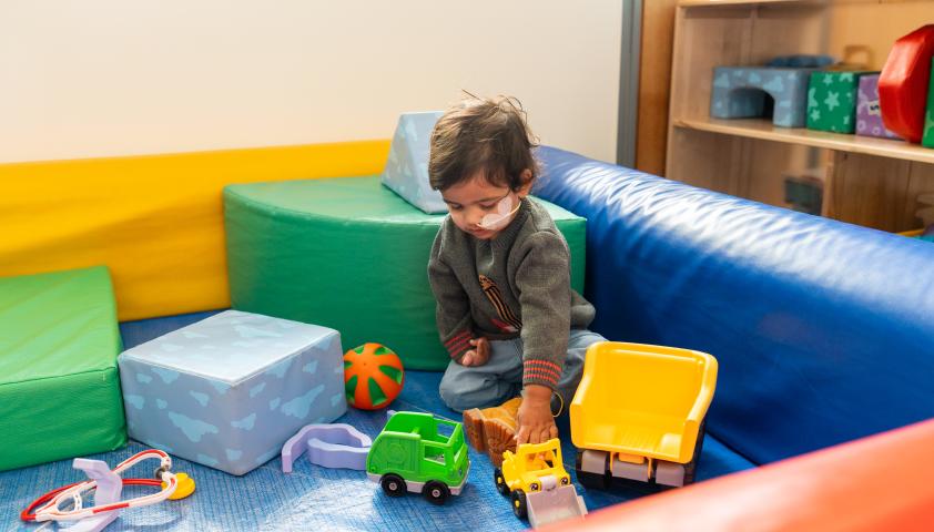 A young boy playing with trucks and toys in a playroom