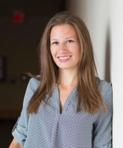 woman with light brown hair smiling wear a blue patterned shirt