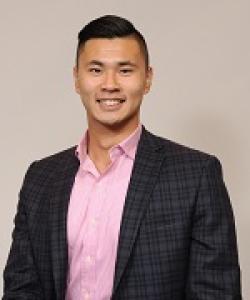 Young man with pink shirt, dark blazer and dark hair.