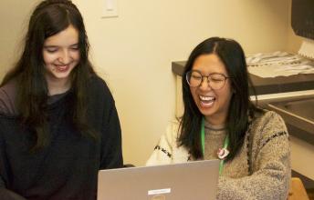 Teen girl and woman laugh at computer screen