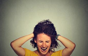 Woman grabs hair and grimaces