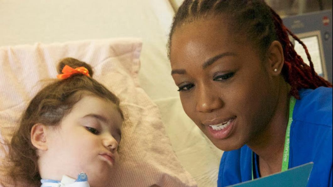 Nurse reads a book to young child with ventilator