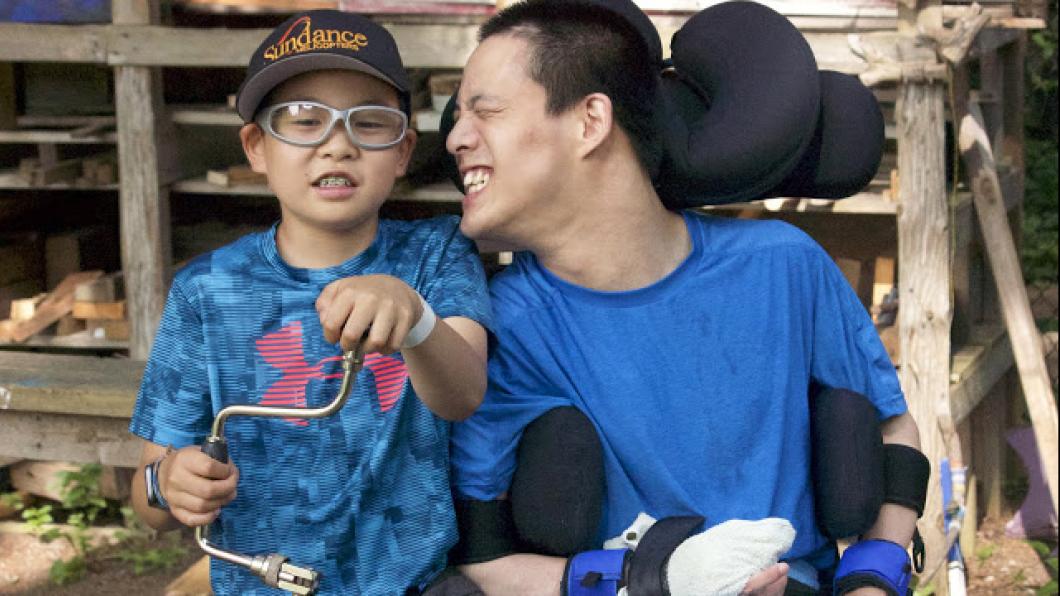 Youth in wheelchair poses with younger boy