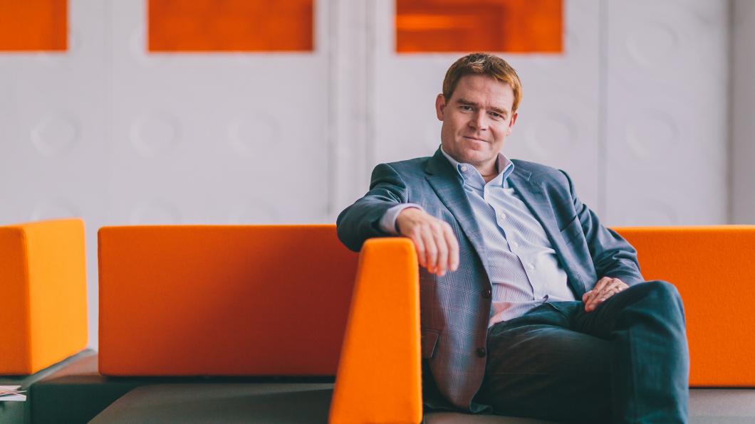 Jason Smith sitting on an orange and green couch