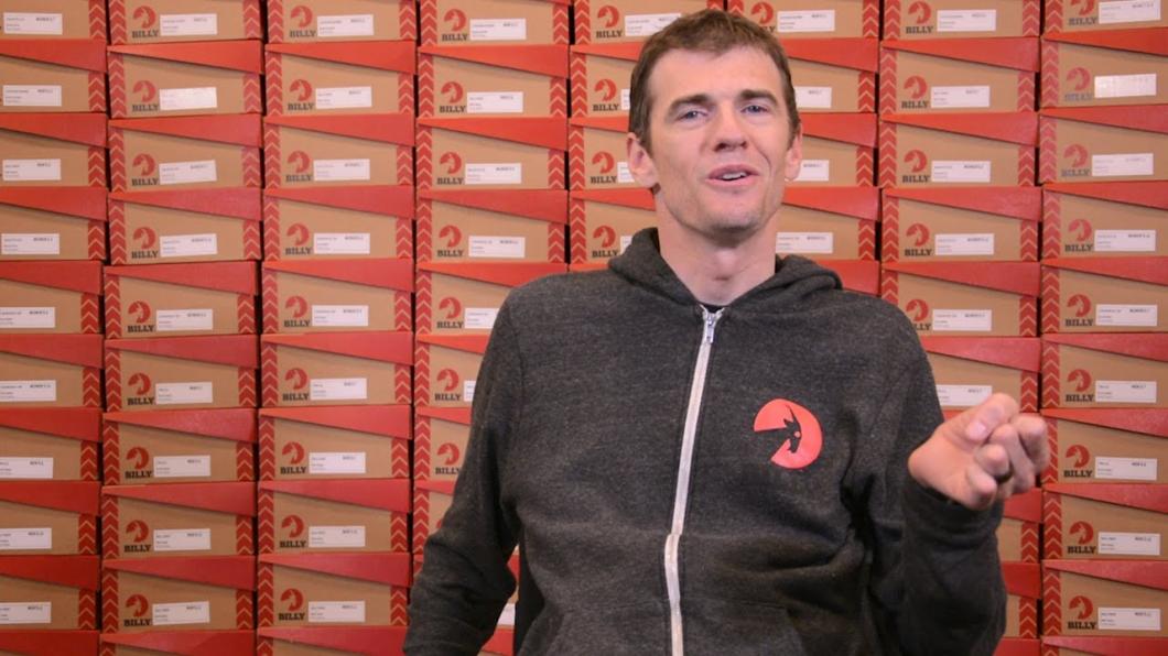 Man sitting ins front of stacks of shoe boxes