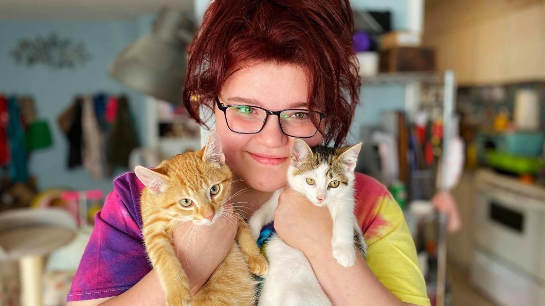 Teen girl holding two kittens
