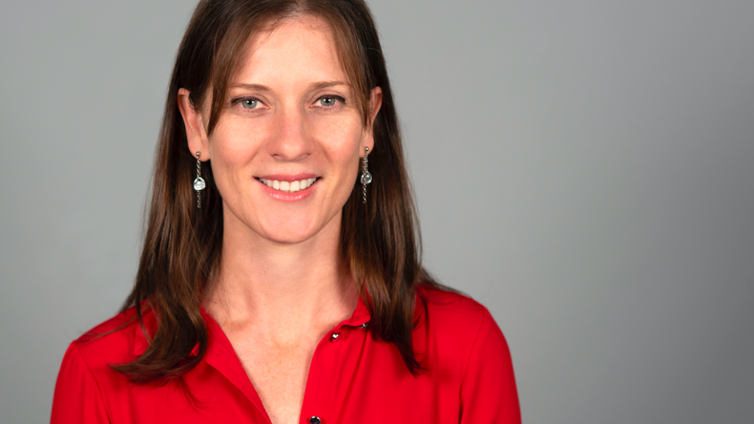 Tracey Smythe smiling at the camera, wearing a red collared shirt.