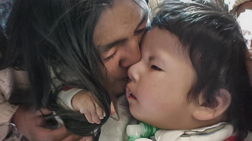First Nations mother kisses face of toddler son
