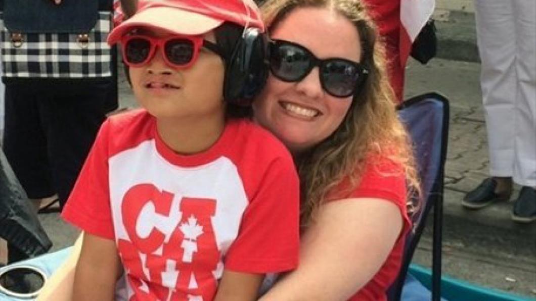 Son on mother's lap in Canada Day clothes and sunglasses and smiles