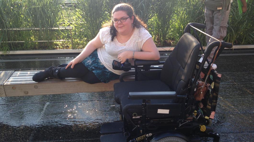 Smiling woman lounging on bench with wheelchair to the side