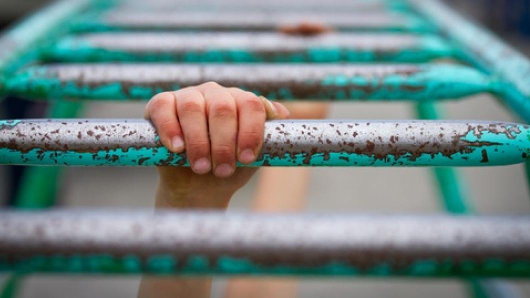 Image of child's hands on green monkey bars