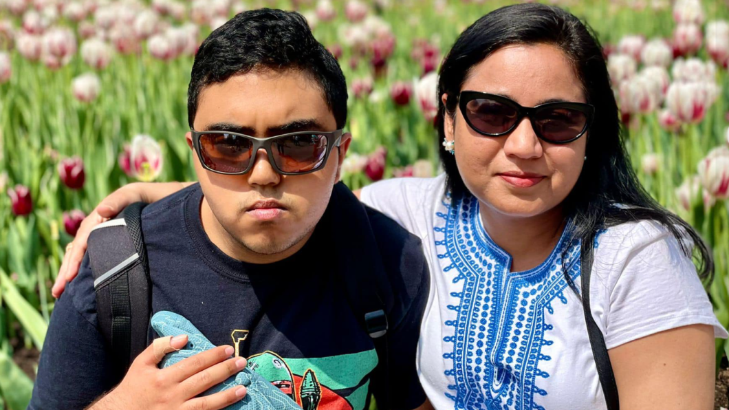 Woman smiling with sunglasses and arm around teen wearing sunglasses