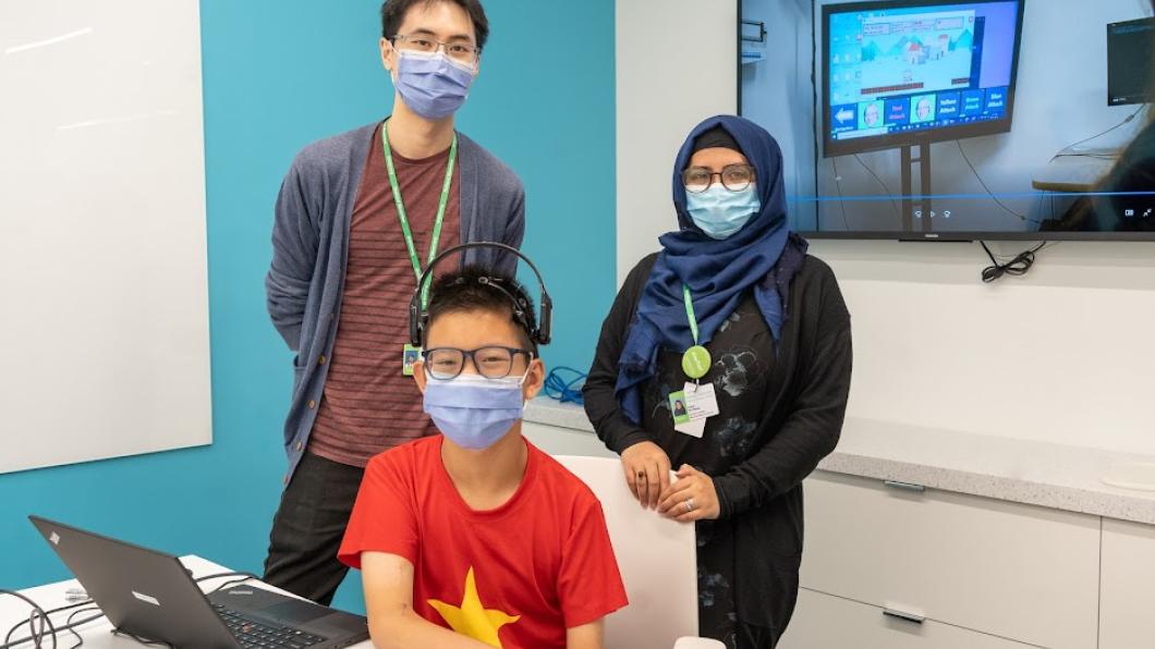 Two adults and a child pose together. The child is using the brain computer interface technology.