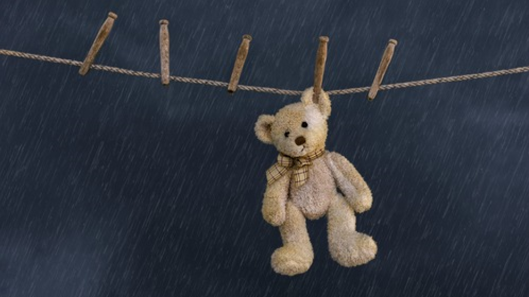 Teddy bear left hanging on the clothes line alone in the rain