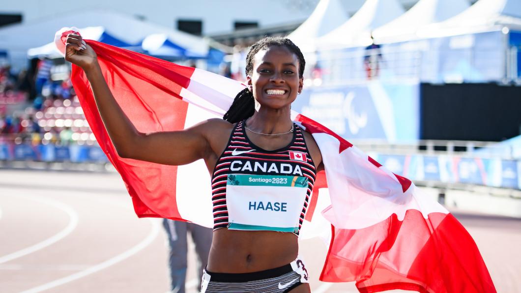 Woman wearing Canada track shirt wrapped in Canadian flag smiles