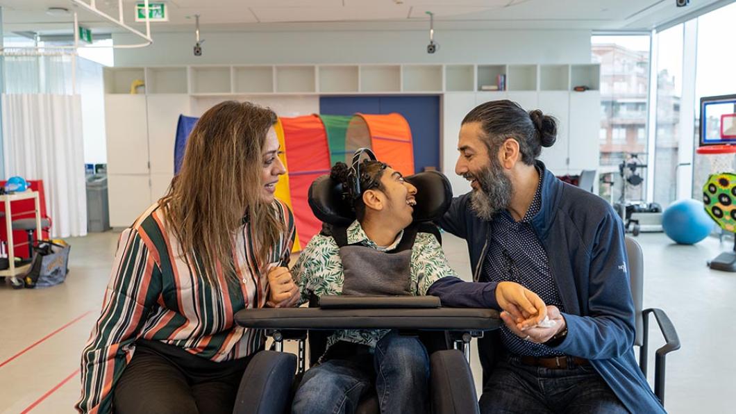 Two adults with a child on a wheel chair